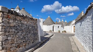 A narrow street lined with stone walls and traditional buildings with conical roofs. - "Nuova Villa Ulivo" among olive and almond trees with private swimming pool (Carovigno)