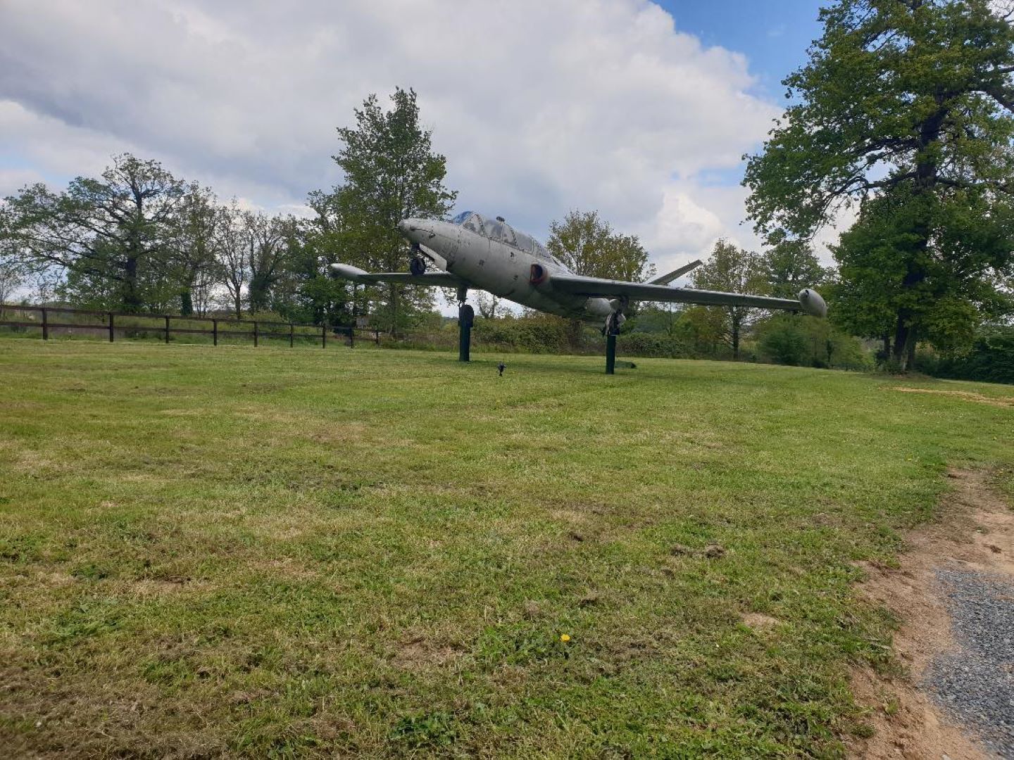 Un velivolo militare d'epoca esposto in un prato, con alberi sullo sfondo.