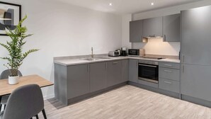 A modern kitchen with grey cabinets, a built-in oven, a microwave, and a sink.