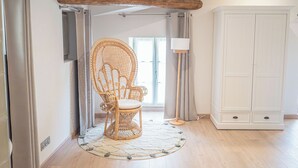 A room with a wicker chair, a white wardrobe, and a floor lamp. - Les Génoises, (Pézenas)