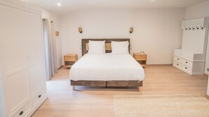 A bedroom with a large bed, bedside tables, a wardrobe, and a mirror. - Les Génoises, (Pézenas)