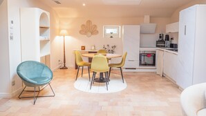 A compact kitchen with a dining area, featuring a round table, chairs, and a built-in oven. - Les Génoises, (Pézenas)