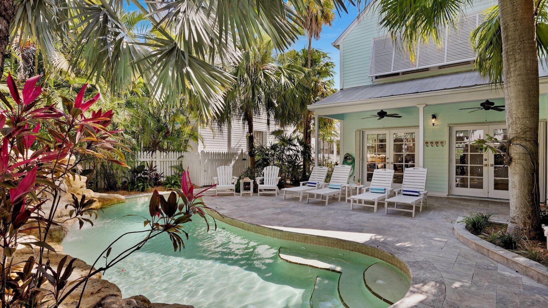 Une piscine entourée de chaises longues, avec une maison en arrière-plan.