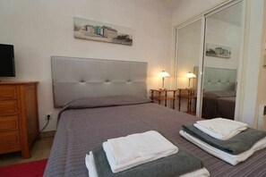 Une chambre à coucher avec un lit, une commode, un miroir et un tableau accroché au mur.