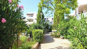 A pathway leading to a building surrounded by lush greenery and flowering plants.