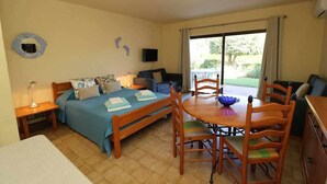 A bedroom with a bed, bedside tables, a desk, a chair, a dining table, and a TV.