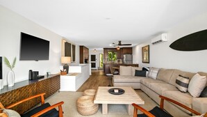 A modern living room with a sofa, coffee table, and a TV mounted on the wall. - Kauai Nihi Kai Villas 507 2 Bedroom Condo (Koloa)