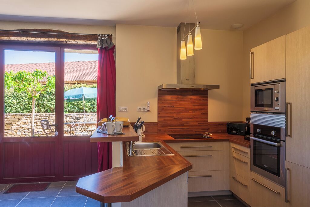 A modern kitchen with a wooden countertop, stainless steel appliances, and a view of the outdoors.