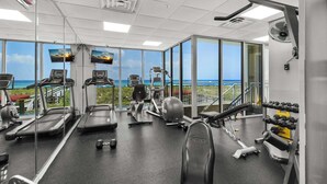 A gym with treadmills, elliptical machines, and weight equipment, overlooking a scenic view.