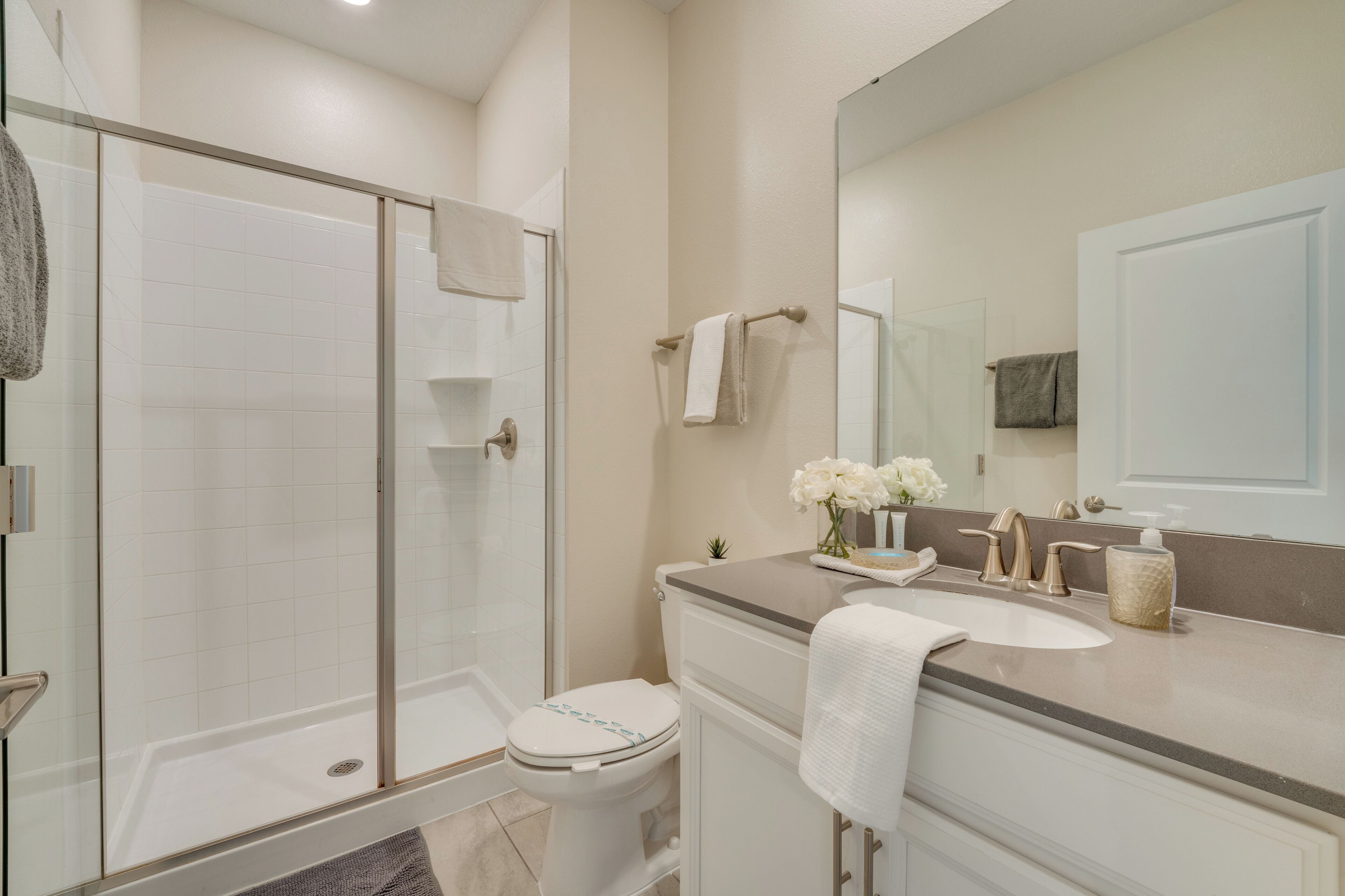 Un bagno moderno con doccia vetro, water bianca e lavabo con specchio.