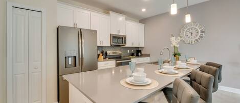 A modern kitchen with white cabinets, stainless steel appliances, and a central island with seating.