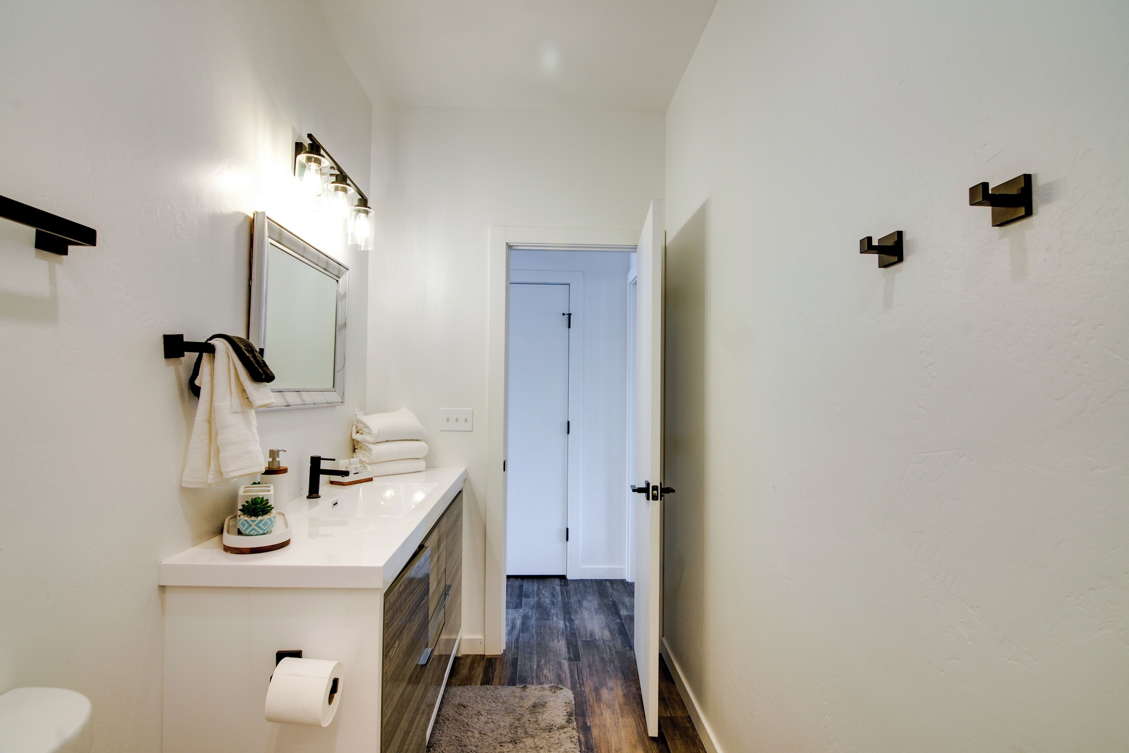 A narrow bathroom with a white sink, a mirror, and a towel rack.