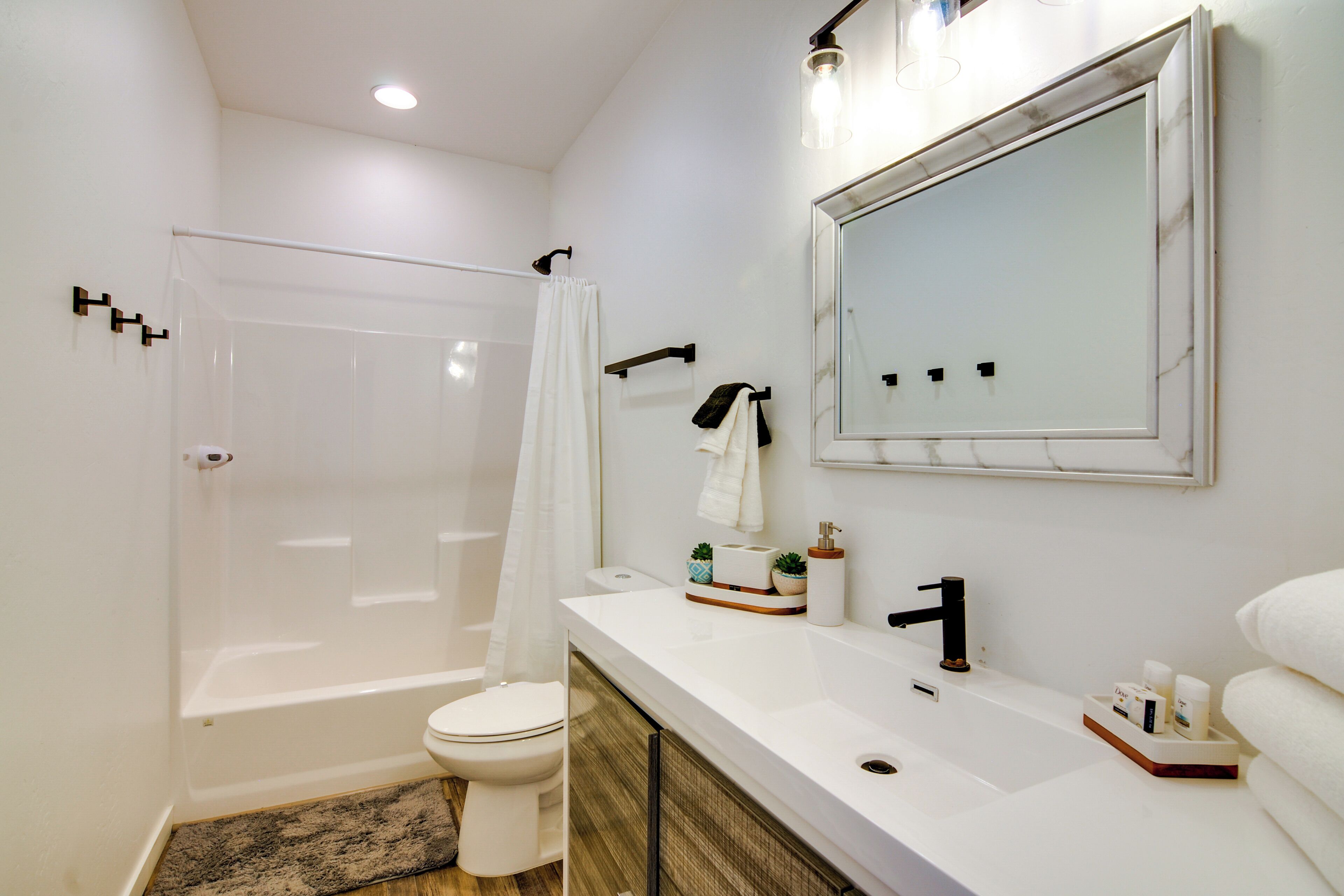 Een moderne badkamer met een badkuip, toilet en een wastafel met spiegel en wasbak.