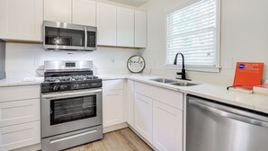 A modern kitchen with white cabinets, stainless steel appliances, a microwave, a stove, and a dishwasher.