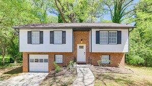A two-story house with a brick facade, a front garage, and a well-maintained lawn.