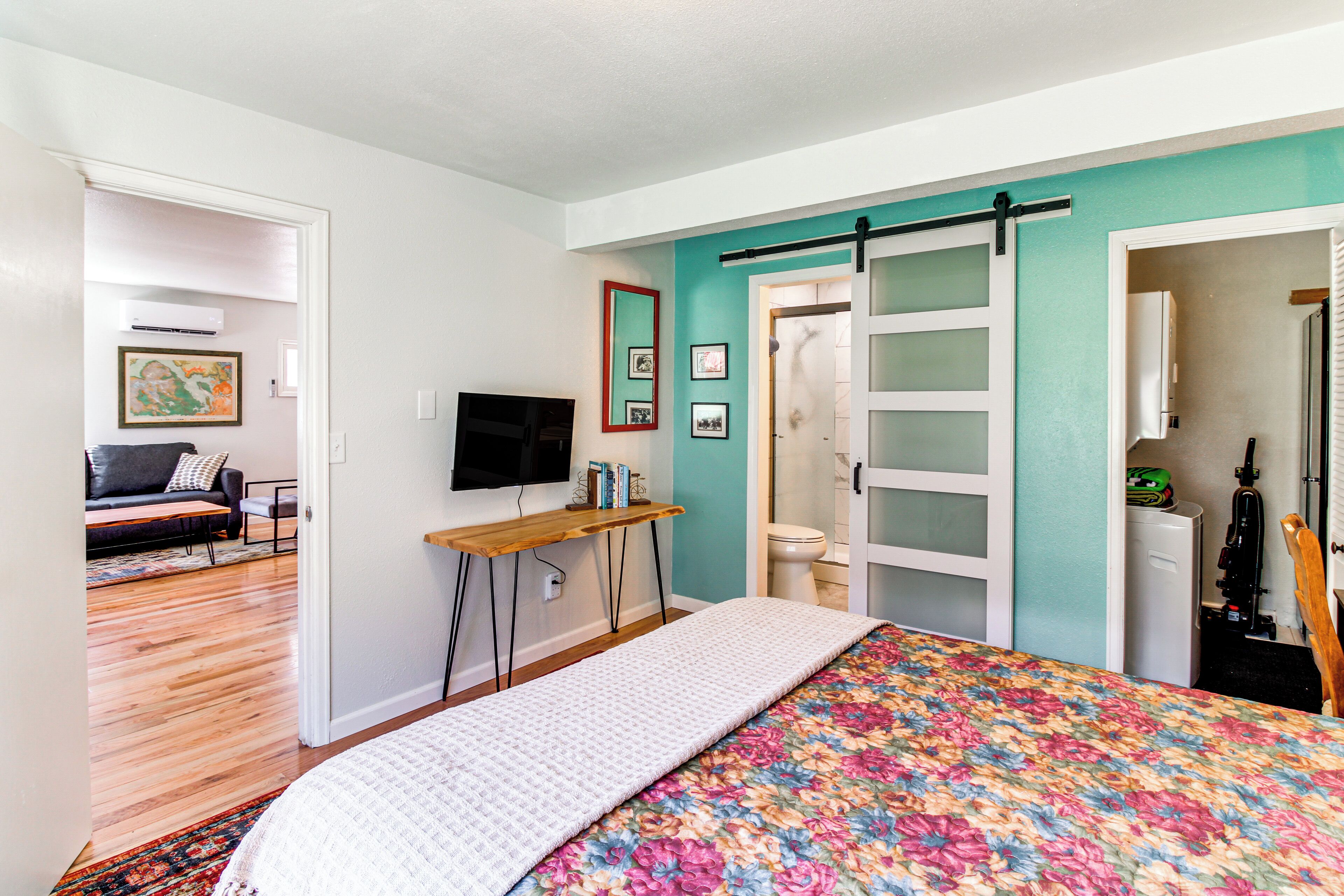 A bedroom with a bed, a desk, a television, and a bathroom.