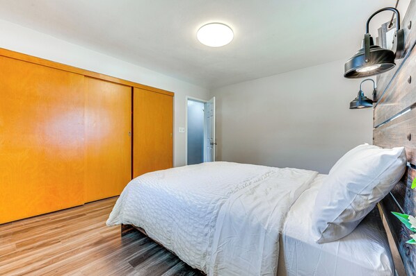 A bedroom with a bed, wooden wardrobe, and a ceiling light.
