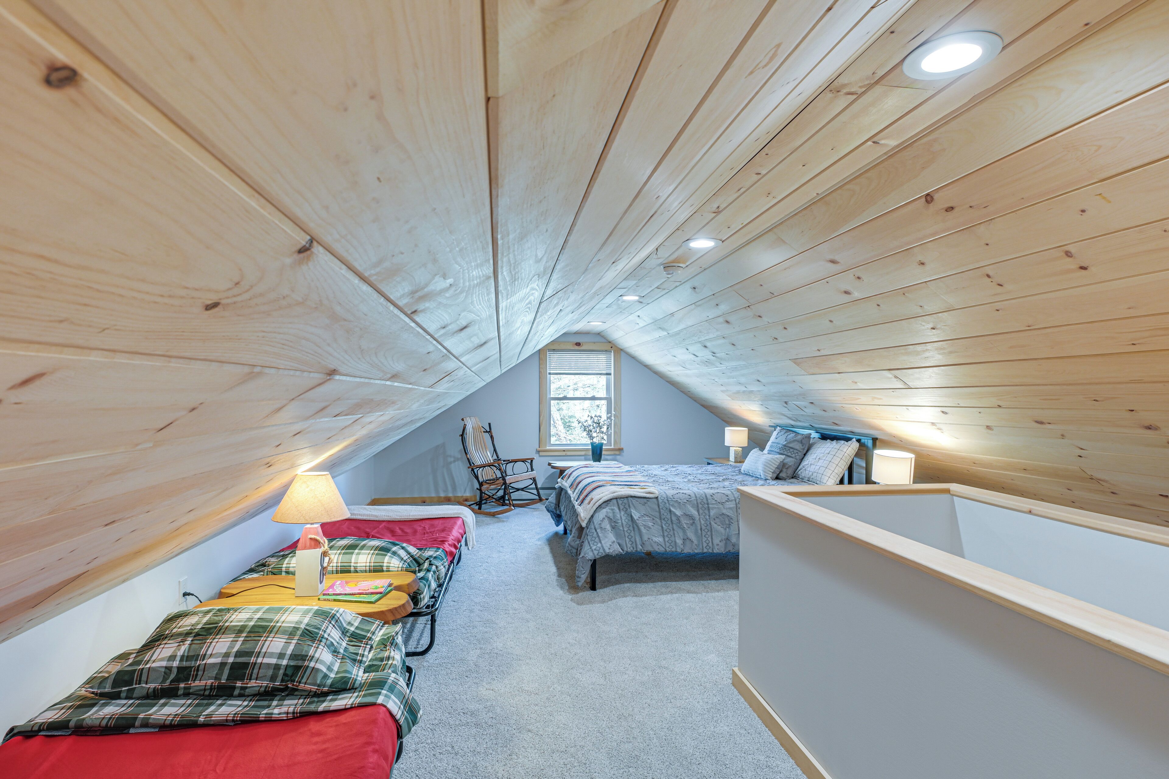 A cozy attic bedroom with two beds, a window, and a sloped ceiling.