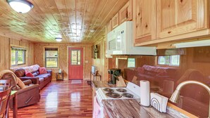 A wooden cabin interior with a kitchen, dining area, and living room.