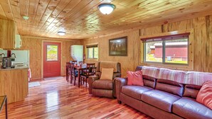 A wooden cabin interior with a dining area, a sofa, and a kitchen.