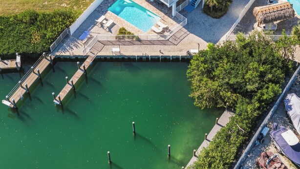 An aerial view of a property with a swimming pool, dock, and a covered outdoor seating area. - Ocean Oasis~  Pool Home, 35' Dock Near Coco Plum Beach! (Marathon)