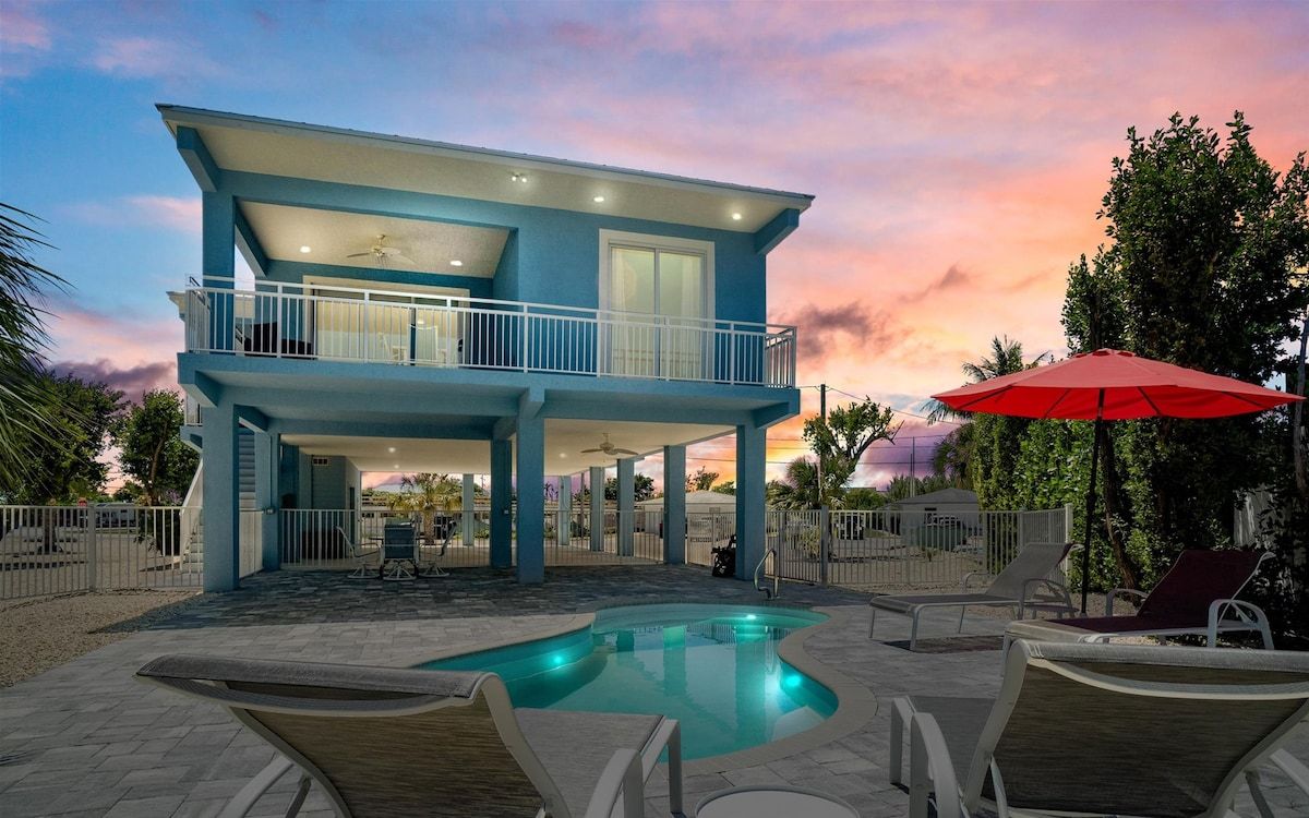 Stunning twilight view highlighting the home's waterfront setting and illuminated pool.