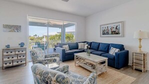 A spacious living room with a blue sofa set, patterned armchairs, a coffee table, and a side table with a lamp. - Ocean Oasis~  Pool Home, 35' Dock Near Coco Plum Beach! (Marathon)