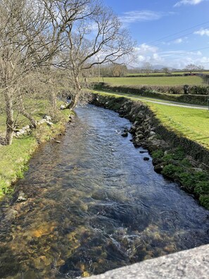 A clear stream with rocks, a stone wall, and a road in the background. - Lovely 3-bed Apartment nr Caernarfon (Caernarfon)