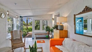 Un espacio habitable amplio con una silla de mimbre, un sofá naranja y un espejo grande.
