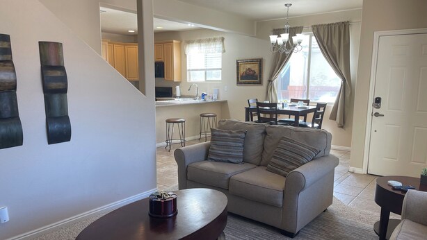A living room with a sofa, a coffee table, and a dining area with a table and chairs. - Lucky Seven Oasis by Mesquite Vacation Rentals with Community Pool and $510 in free daily activities (Mesquite)