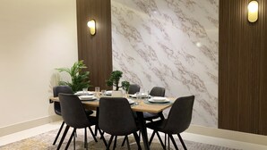 A dining area with a marble wall, wooden paneling, and modern chairs. - Kease Tawun B3-1 Royal touch  AG72 (Riyadh)
