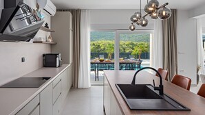 Una cocina moderna con una isla central, un comedor con vistas a un jardín exuberante y un ventanal grande.