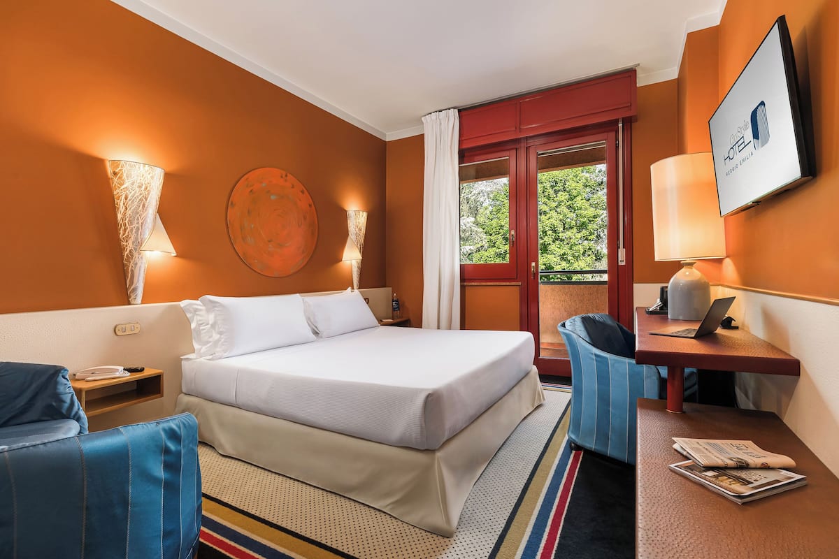 Ein Hotelzimmer mit Bett, Schreibtisch, Stuhl und Fernseher.
