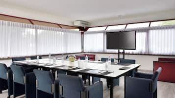 A conference room with a large table, chairs, a projector screen, and a water dispenser.