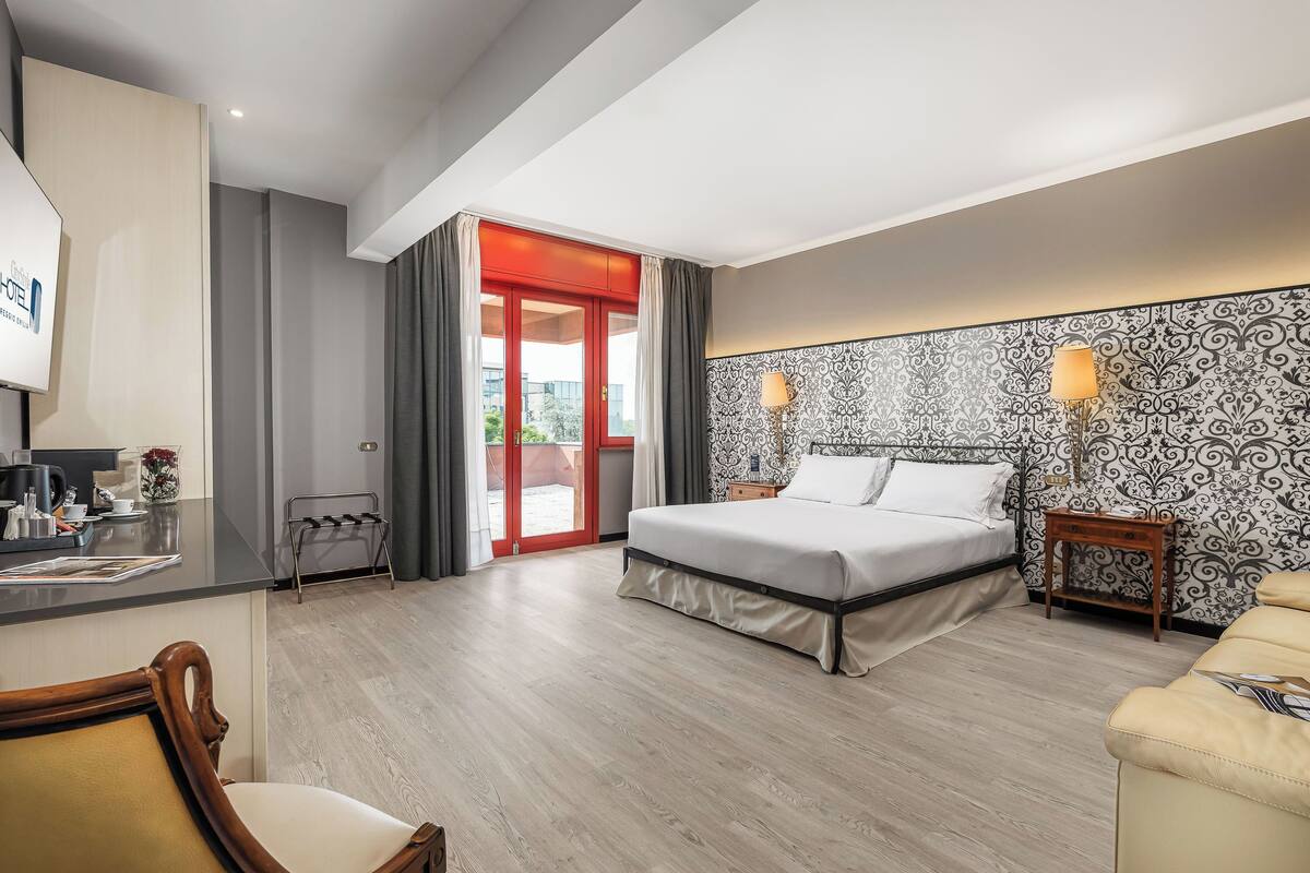 Ein Hotelzimmer mit Bett, Nachttischen, einem Schreibtisch mit Stuhl und Blick nach draußen.