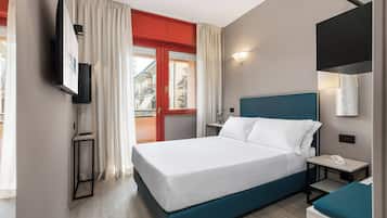 A hotel room with a bed, bedside table, and a TV mounted on the wall.