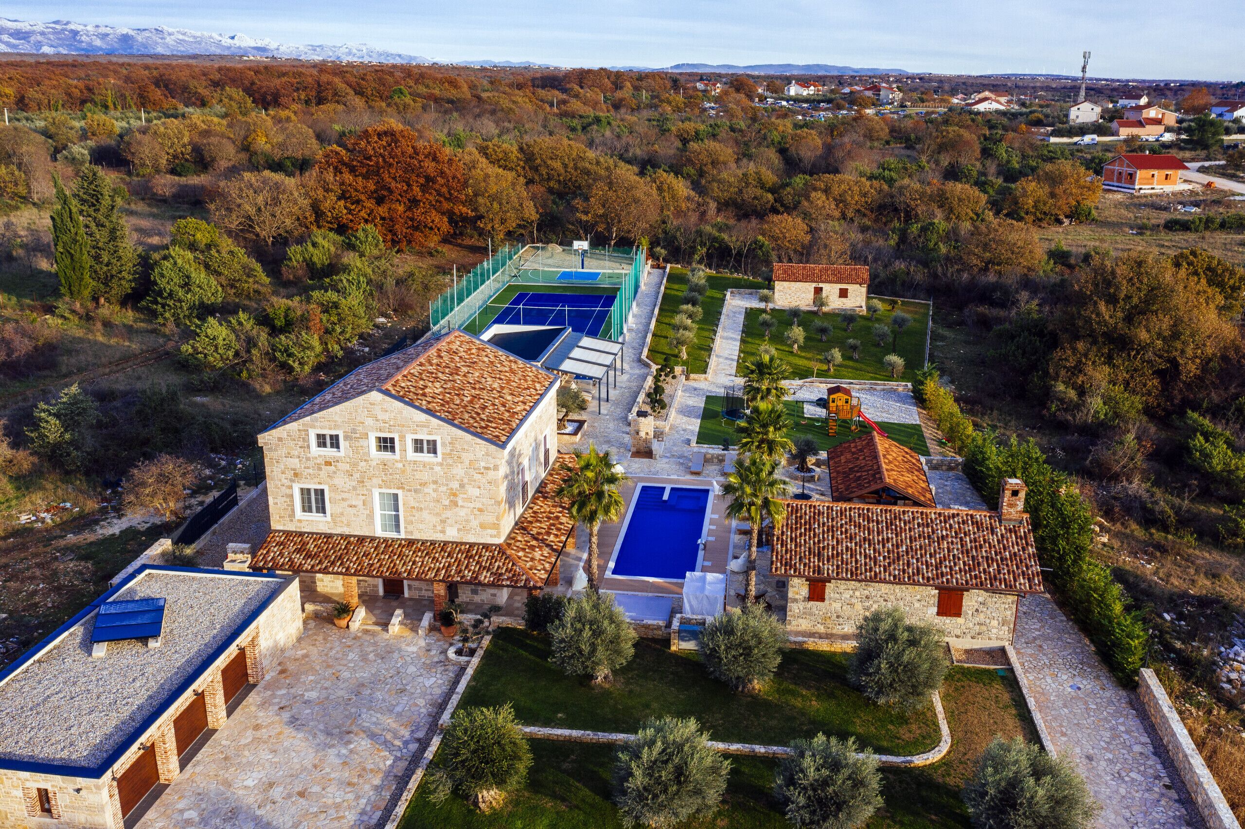A villa with multiple swimming pools, a tennis court, and a well-maintained garden.