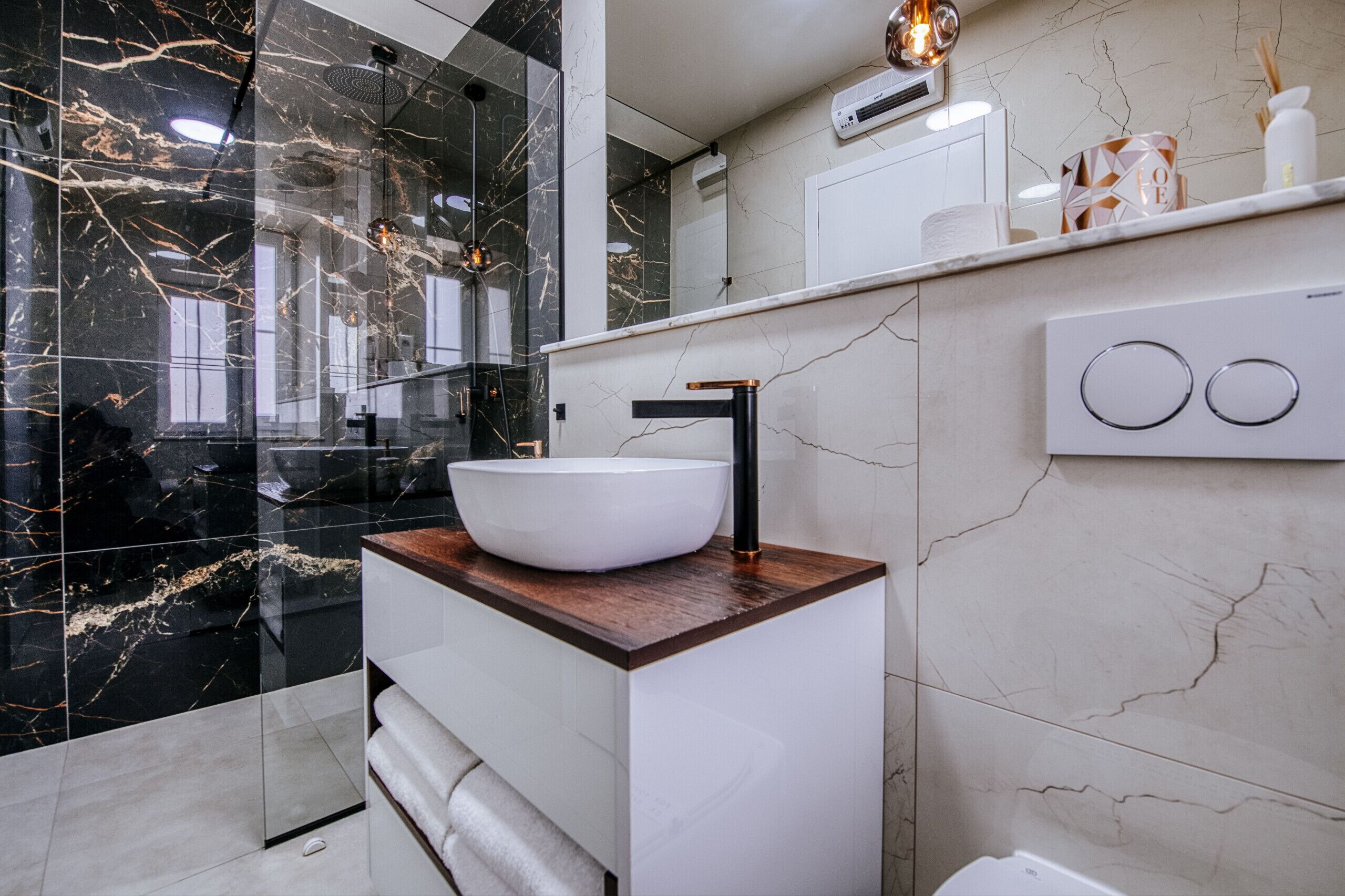 A modern bathroom with a white vessel sink, a wooden countertop, and a large mirror.