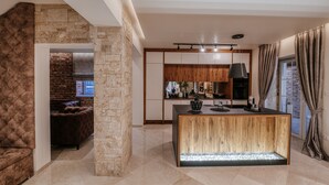 Une cuisine moderne dotée d’un îlot central, de murs en pierre et d’un coin salon confortable avec une cheminée.