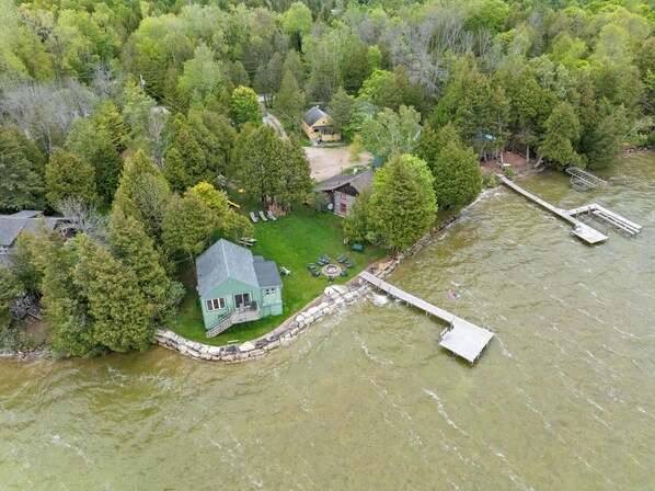 A lakeside property with a house, dock, and surrounding forest.