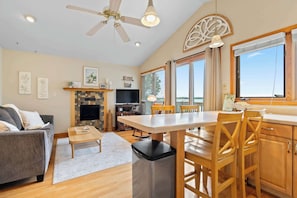 A spacious living area with a fireplace, a dining table, and a kitchen with wooden cabinets.