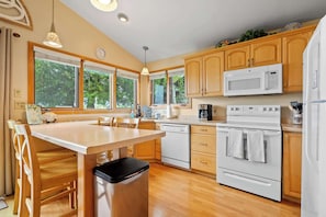 A kitchen with wooden cabinets, a white stove, a microwave, and a dishwasher.