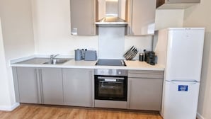 A modern kitchen with stainless steel appliances, a built-in oven, and a dishwasher. - 2 Bed City Centre Flat | Free Parking (Manchester)