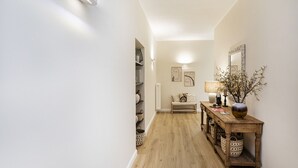 A hallway with a wooden floor, a wooden console table with baskets, a lamp, and wall art. - Sea View Flat in Rapallo by Wonderful Italy (Rapallo)