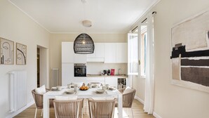 A modern kitchen with white cabinets, a black oven, and a hanging light fixture. - Sea View Flat in Rapallo by Wonderful Italy (Rapallo)