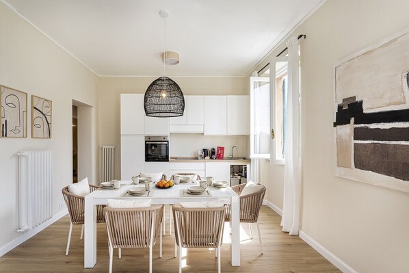 A modern kitchen with white cabinets, a black oven, and a hanging light fixture. - Sea View Flat in Rapallo by Wonderful Italy (Rapallo)