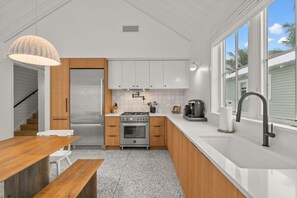 A modern kitchen with white cabinets, a stainless steel refrigerator, a gas stove, and a sink.