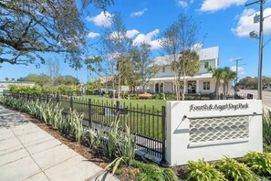 A sign for Fourth & Angel Dog Park with a paved walkway and a black fence.