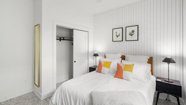 A bedroom with a bed, nightstands, a wardrobe, and two framed pictures on the wall.