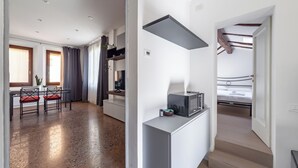 A modern apartment with a kitchen area, a dining table with chairs, a bed, and a staircase. - Casa Picta (Bologna)
